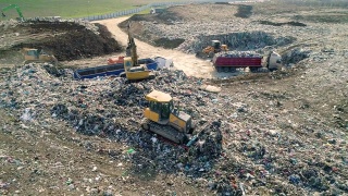 城市垃圾场。推土机沿着垃圾填埋场移动，铲平垃圾。鸟瞰图视频素材模板下载