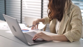 亚洲女商人在办公室用笔记本电脑工作视频素材模板下载