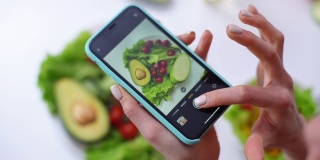 用手机的相机拍蔬菜沙拉的女人的特写。