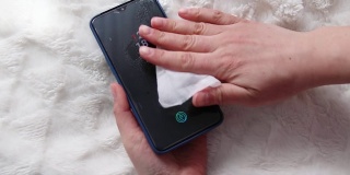 女性手喷雾洗手液在手机上清洁和防止病毒，细菌和细菌的特写