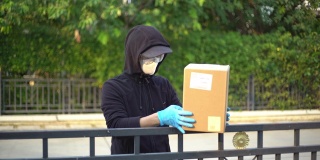 快递员戴上安全眼镜和面罩，将包裹放在围栏上，保持距离，减少细菌传播