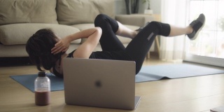 亚洲女性在家用笔记本电脑健身