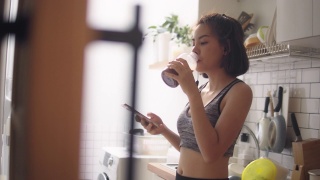在家锻炼后喝蛋白质奶昔的健康女性视频素材模板下载