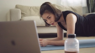 亚洲女性在家用笔记本电脑健身视频素材模板下载