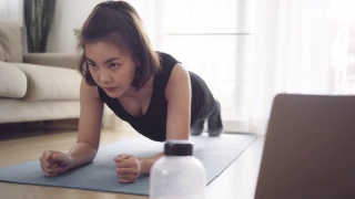 亚洲女性在家用笔记本电脑健身视频素材模板下载