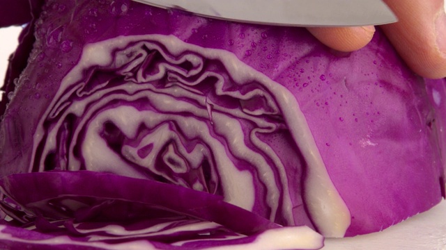 厨师将紫色或红色卷心菜用刀切在砧板上。4 k DCI slowmotion。