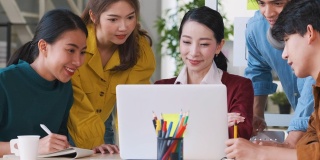 亚洲女性领导者建议ux/ui设计师在现代办公室的桌上进行手机应用界面线框图设计。创意数字发展机构，放松会议