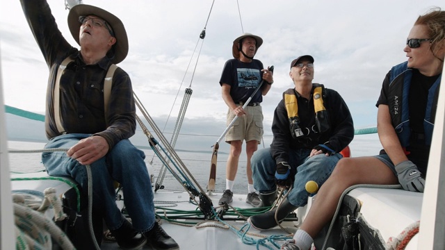 华盛顿州西雅图附近的普吉特海湾，一群人坐在一艘帆船的甲板上交谈