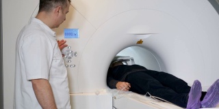 男性病人正在进行ct扫描。医疗设备:诊断门诊用计算机体层摄影机。健康的概念。医生按下CT MRI扫描仪设置按钮。高清
