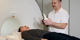 计算机断层摄影的概念。健康的概念。现代医院采用磁共振成像仪对病人进行扫描。身穿白大褂的男性放射科专家戴上眼镜，为病人进行CT核磁共振检查做准备。高清