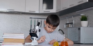 一个男孩用显微镜学习生物，并在笔记本上做笔记。家庭作业