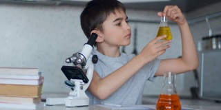 特写镜头。一个男生用显微镜和装有液体的烧瓶教化学，并在笔记本上做笔记。家庭作业