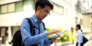 亚洲旅行者从纸上和智能手机上看地图