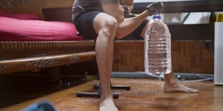 在covid-19或冠状病毒感染的情况下，亚洲男性在家使用塑料瓶装水而不是健身房举重物进行锻炼