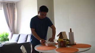 一名亚洲华人中年男子在冠状病毒隔离期间呆在家里享用中餐午餐盒饭视频素材模板下载