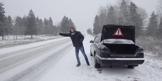 那个人寻求帮助，车子在冬天的路上抛锚了。试图拦住一辆过路的汽车。