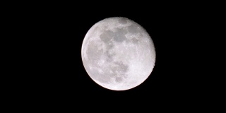 特写满月与黑色的天空背景在晚上，云移动和月光闪烁，长焦镜头全高清视频。