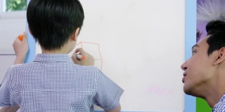 亚洲家庭的生活方式父母和儿子在家里通过在白板上创作艺术来进行教育活动。创造微笑和乐趣。