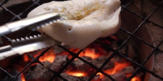 切片鱿鱼放在传统的炉子上烤。泰国海鲜菜单，味道鲜美。泰国街头小吃菜单。燃烧着木炭，下面有炽热的火焰。热菜单，适合野餐。缓慢的运动。