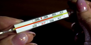 妇女手上的医用体温计用动画显示，COVID-19全球大流行期间温度上升至39摄氏度