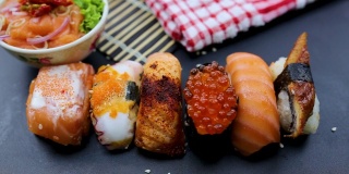 日本食品成分。各种寿司放在黑板上。辣泡菜三文鱼色拉配筷子。