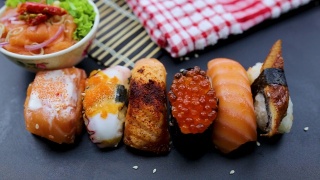 日本食品成分。各种寿司放在黑板上。辣泡菜三文鱼色拉配筷子。视频素材模板下载