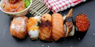 日本食品成分。各种寿司放在黑板上。辣泡菜三文鱼色拉配筷子。
