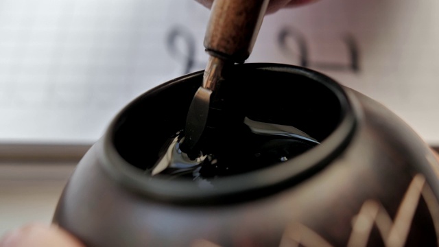 特写的木制钢笔尖端放置在黑色墨水池
