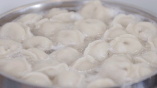 在平底锅中加入香料在水里煮饺子。饺子是俄罗斯的传统食物。食品的背景。视频素材模板下载