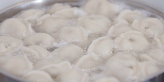 在平底锅中加入香料在水里煮饺子。饺子是俄罗斯的传统食物。食品的背景。