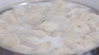 用慢动作煮饺子。在平底锅中加入香料在水里煮饺子。饺子是俄罗斯的传统食物。食品的背景。视频素材模板下载