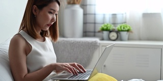 年轻的亚洲女性使用笔记本电脑在家工作