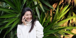 一名年轻的亚洲女子边走边用耳机打电话