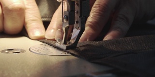 一名男子在缝纫机上缝防护口罩。特写镜头