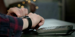 一名男子在咖啡馆用电子智能手表付款。非接触式NFC技术。网上购物使用现代技术。消费主义网上购物。男人正在用智能手表支付