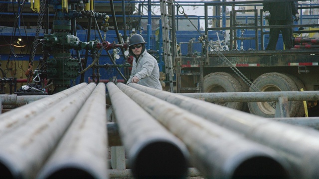 一个20多岁的年轻油田工人在一个寒冷的早晨在石油和天然气钻井平台上测量钻杆的慢动作镜头