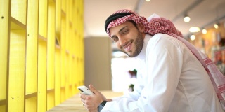 阿拉伯中东男子在便利店使用手机的肖像
