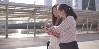 两位亚洲女商人在上班路上使用智能手机
