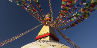 尼泊尔加德满都，博德纳斯塔周围的彩旗。许多鸟坐在底部。蓝色的天空和白色的月亮。UHD