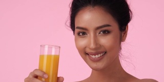 美丽的亚洲女孩喝橙汁。拿着玻璃杯的漂亮女孩，果汁和排毒饮料。饮料、保健、食品饮料的概念。