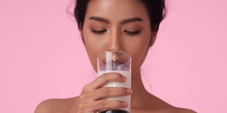 美丽的亚洲女孩喝牛奶。拿着牛奶杯的漂亮女孩趁机解毒。饮料、保健、食品饮料的概念。