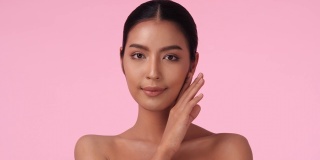 美丽的亚洲女人的肖像展示和摆出健康的美丽在孤立的粉红色背景。美容、美容、保健、时尚和护肤的概念。4 k UHD。