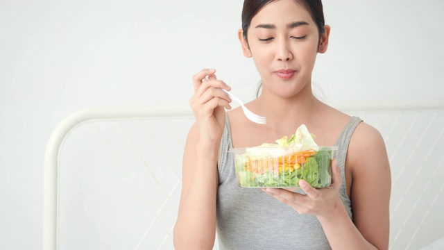美丽的亚洲女孩吃解毒蔬菜和水果。漂亮女孩拿着水果沙拉和排毒食品。健身、保健、饮食的概念。