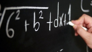手持粉笔，在黑板上写下复杂复杂的数学公式。视频素材模板下载