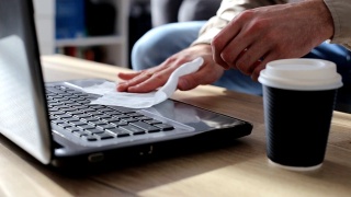 一名男子用消毒湿巾擦拭笔记本电脑。笔记本电脑消毒。疾病的预防视频素材模板下载