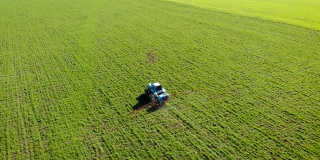 蓝色复古拖拉机喷洒小麦或大麦与液体化学品的鸟瞰图