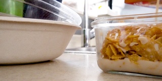 添加豆浆到玻璃容器与早餐谷物玉米片特写