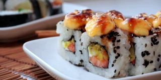 白盘子上的寿司特写，鳄梨，奶油芝士，芝麻。日本餐厅的菜单