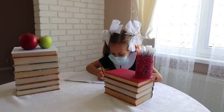 戴面具的女学生做家庭作业。冠状病毒self-isolation