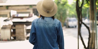 年轻的亚洲女性旅行者戴着复古软呢帽走在泰国曼谷的街道上。享受夏日假日旅游。单独旅行的概念。